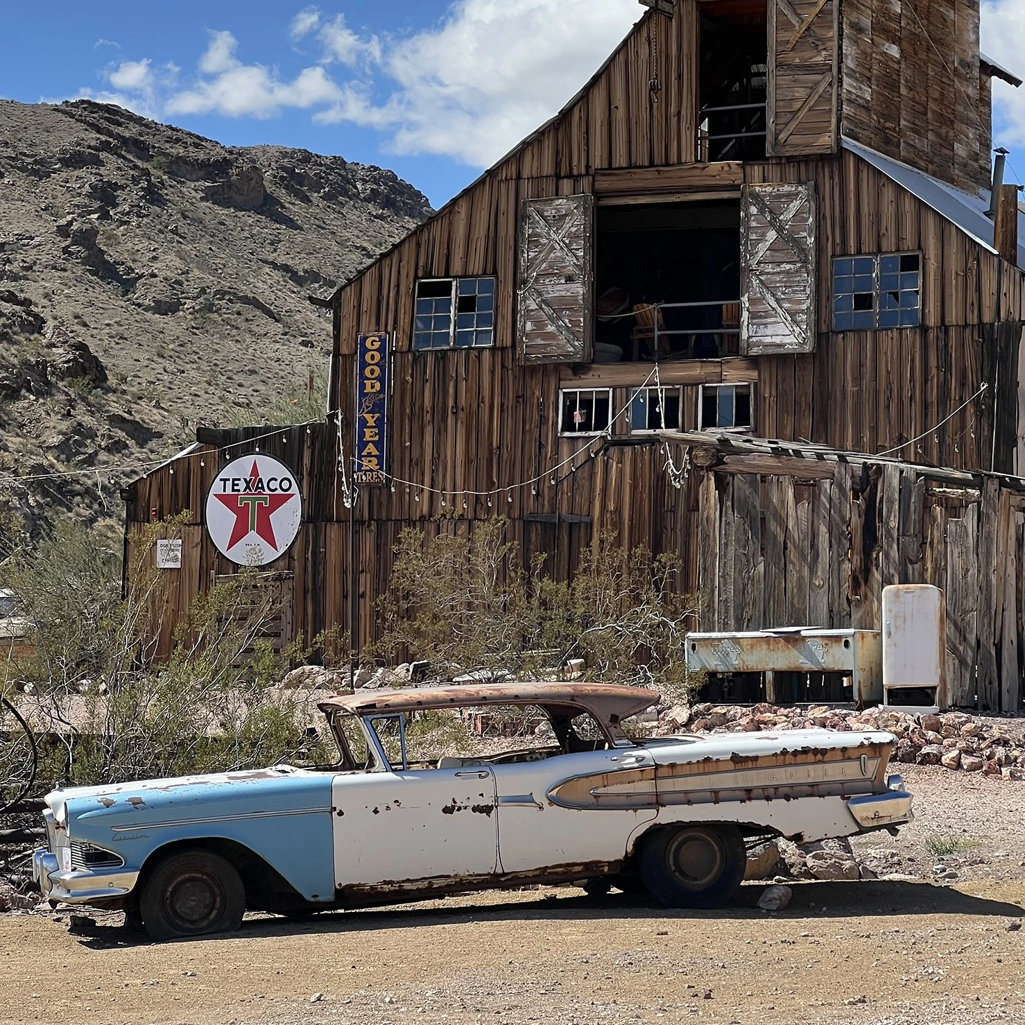 A vintage car in front of weathered wooden buildings in Nelson Ghost Town, Nevada